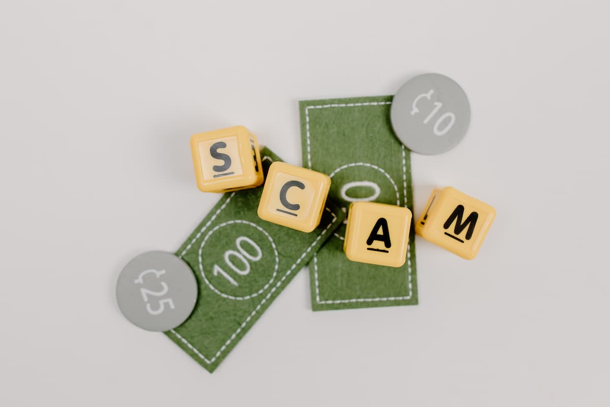 scrabble letters spelling out the word scam with toy money in the background